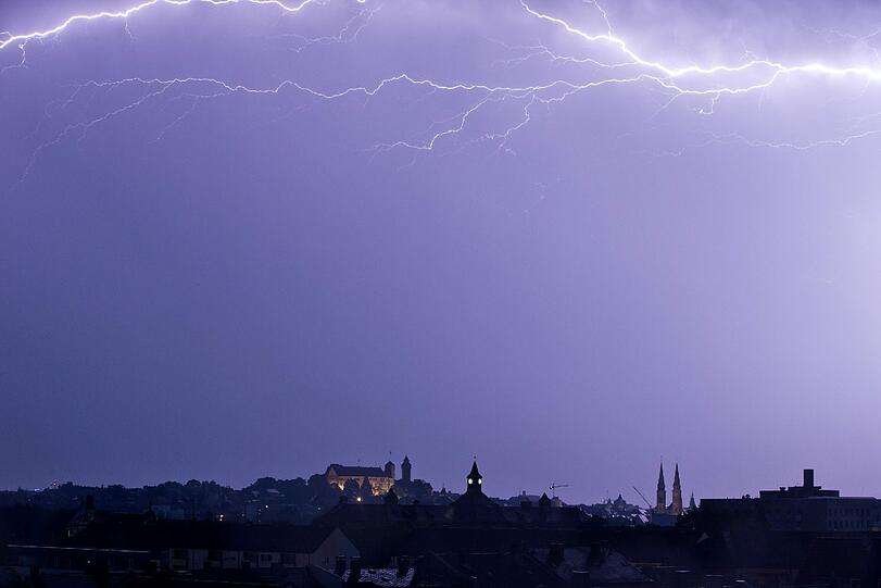 Ein Blitz erleuchtet den Nachthimmel über der Altstadt und der Kaiserburg in Nürnberg.