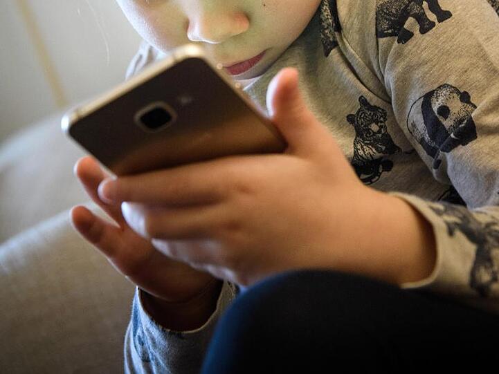 Ein kleines Mädchen spielt auf einem Smartphone.