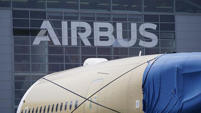 Ein Segment eines Flugzeugrumpfes steht vor einer Fertigungshalle auf dem Werksgelände von Airbus.
