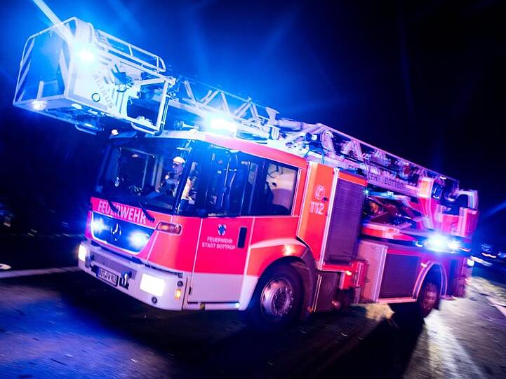 Ein Drehleiterwagen der Feuerwehr fährt mit Blaulicht an einer Unfallstelle vorbei. Foto: Marcel Kusch/dpa/Illustration