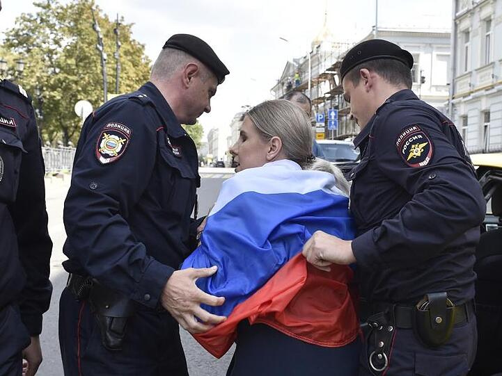 Russische Polizeibeamte verhaften eine Oppositionelle bei der nicht genehmigten Kundgebung im Zentrum der Stadt. Nach den Massenfestnahmen bei den Protesten in der russischen Hauptstadt Moskau sind mehr als 40 Demonstranten zu Arreststrafen verurteilt worden.