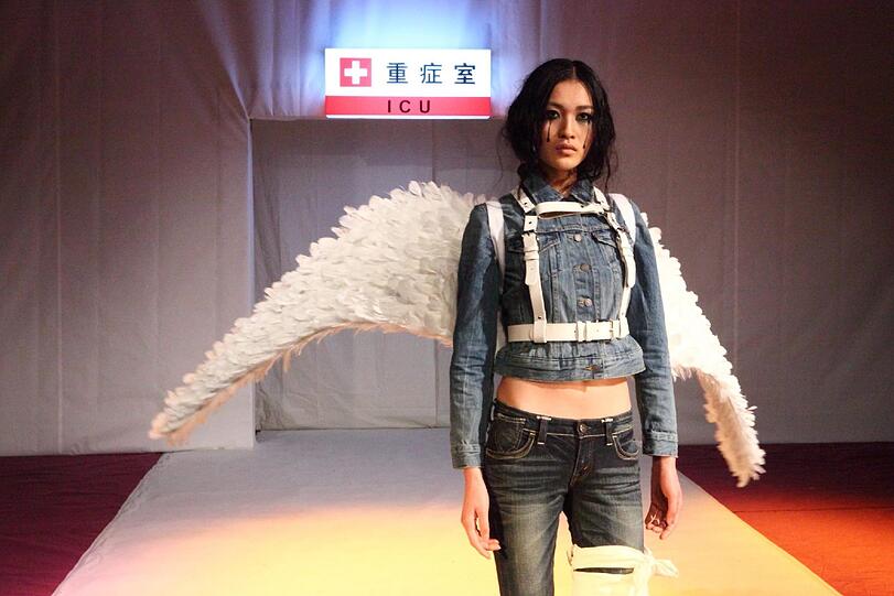 Eine besondere Aktion: Ein Model in Peking mit Beinbinde soll die giften Kleidung der großen Modemarken symbolisieren