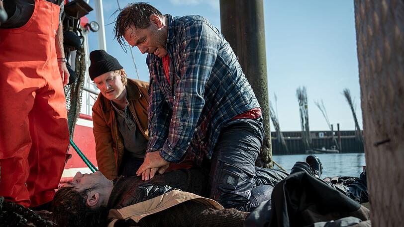 Götz Fischer (Max Hopp, rechts) hat seinen Schützling Hark "Harke" Petersen (Eren Yilmaz, liegend) aus dem Wasser gezogen. Niels Schneider (Leo Meier) will helfen, doch es ist zu spät. Götz Fischer (Max Hopp, rechts) hat seinen Schützling Hark "Harke" Petersen (Eren Yilmaz, liegend) aus dem Wasser gezogen. Niels Schneider (Leo Meier) will helfen, doch es ist zu spät.