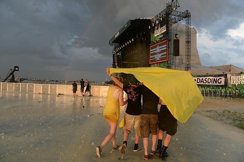 Festivalbesucher verlassen am ersten Tag des "Southside Festivals" wegen einer Unwetterwarnung bei Regen das Festivalgelände.