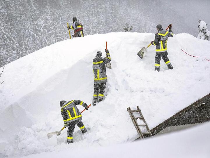 Feuerwehleute räumen den Schnee von einem Dach im österreichischen Annaberg.