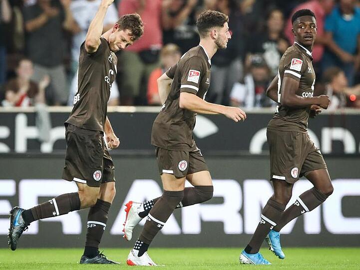 St. Paulis James Lawrence (l-r), Matt Penney und Christian Conteh feiern das Tor zum 1:0 gegen Holstein Kiel.