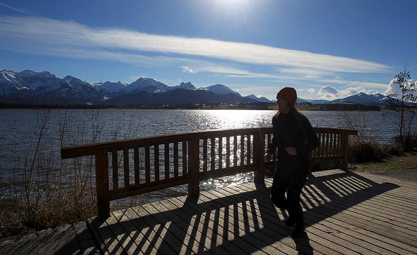 Eine Joggerin läuft am 19.03.2013 vor dem im Sonnenschein glitzernden Hopfensee. Am 20.03.2013 ist kalendarischer Frühlingsanfang. Foto: Karl-Josef Hildenbrand/dpa