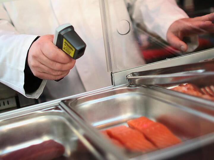 Ein Kontrolleur misst die Temperatur von Lachsfilets.