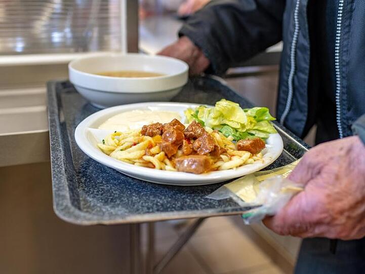 Ein Mann bekommt in der Fürstlichen Notstandsküche im Schloss St. Emmeram ein Essen. Foto: Armin Weigel/Archiv