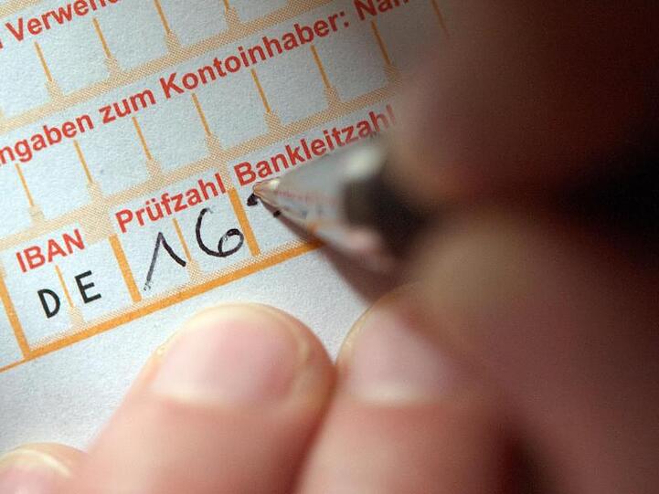 Bald nur Kostenpflichtig? Eine Frau füllt ein Überweisungsformular aus.