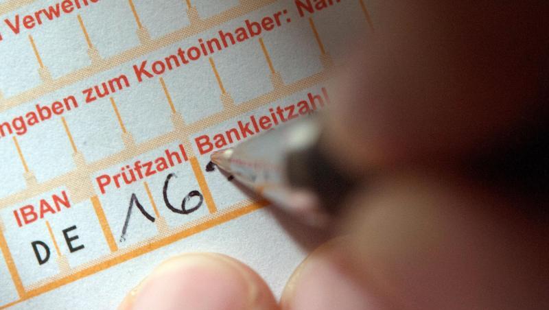 Bald nur Kostenpflichtig? Eine Frau füllt ein Überweisungsformular aus.
