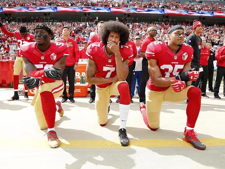 Colin Kaepernick (M), Eli Harold (l) und Eric Reid von den San Francisco 49ers knien 2016 beim Abspielen der US-Nationalhymne.