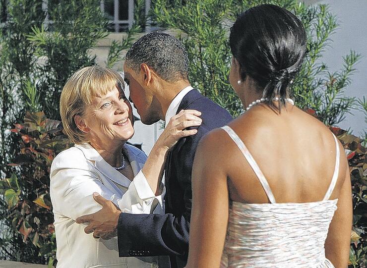 Er küsst, sie guckt: US-Präsident Barack Obama begrüßt Kanzlerin Angela Merkel. Michelle Obama (von hinten) schaut zu. Foto: Reuters