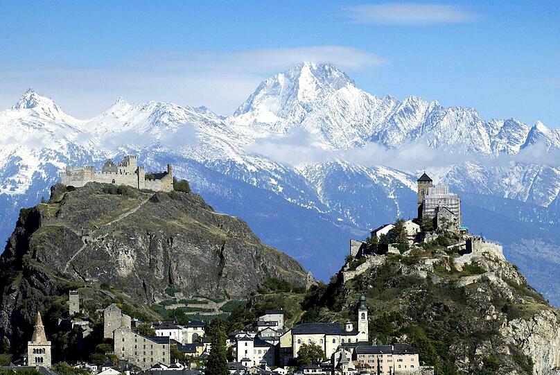 Vielleicht wegen dieses Panoramablicks? Die Schweiz ist das beliebteste Ausreiseziel der Deutschen. Hier erheben sich die zwei Burghügel mit der Basilika von Valeria (rechts) und das Schloss Tourbillon vor dem Bietschhorn.
