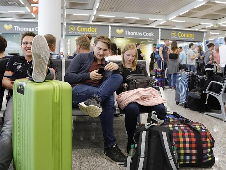 Passagiere warten in der Nähe des Büros von Condor und Thomas Cook im Flughafen von Palma de Mallorca.
