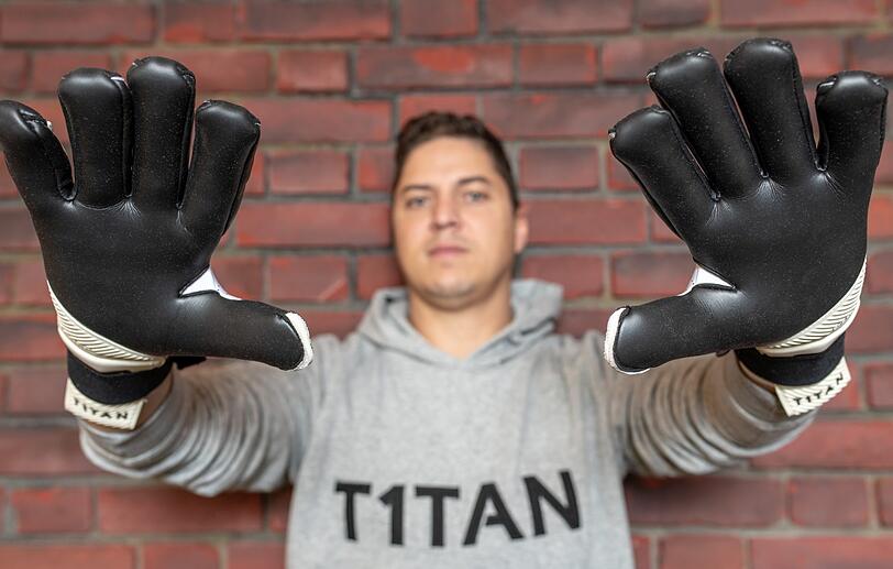 Matthias Leibitz, Geschäftsführer der T1TAN GmbH, steht in den Geschäftsräumen und trägt Torwarthandschuhe, die sein Unternehmen herstellt.