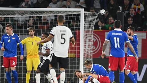 Yarik Frick (M.r.) aus Liechtenstein beugt sich nach einem Foul an Leon Goretzka über den Verletzten.