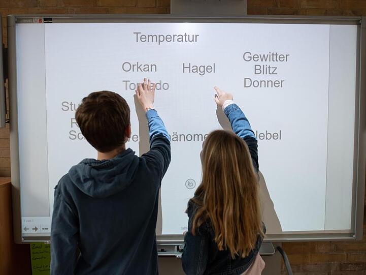 Ein Schüler und eine Schülerin arbeiten an einem Smartboard.