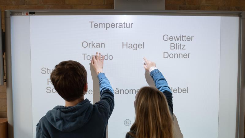 Ein Schüler und eine Schülerin arbeiten an einem Smartboard. Ein Schüler und eine Schülerin arbeiten an einem Smartboard.