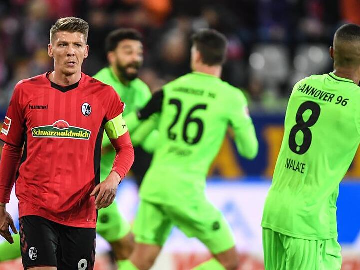 Hinter Mike Frantz (l) vom SC Freiburg feiern die Spieler von Hannover 96 das 1:1.