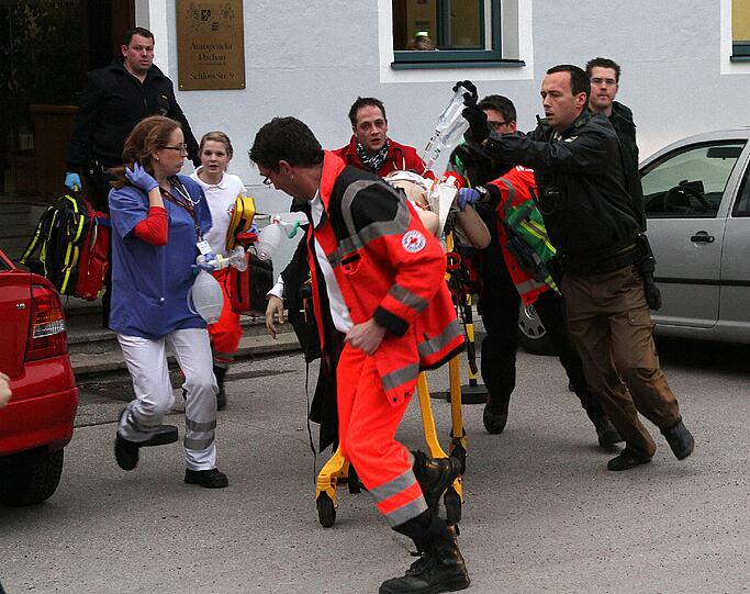 Bluttat in Dachau: Ein schwerverletzter 31-jähriger Staatsanwalt wird zum Notarztwagen gebracht. Im Gerichtssaal hatte ein Angeklagter erst auf den Richter gezielt. Dann schoss er drei Kugeln in den Oberkörper des Staatsanwalts. Der Mann stirbt auf dem Weg ins Krankenhaus.