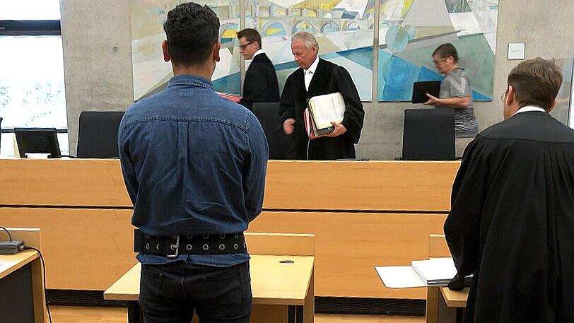 Der Angeklagte (Mitte) steht im Sitzungssaal: Weil er Frauen vergewaltigt und heimlich gefilmt haben soll, muss sich der 30-Jährige in Würzburg vor Gericht verantworten.