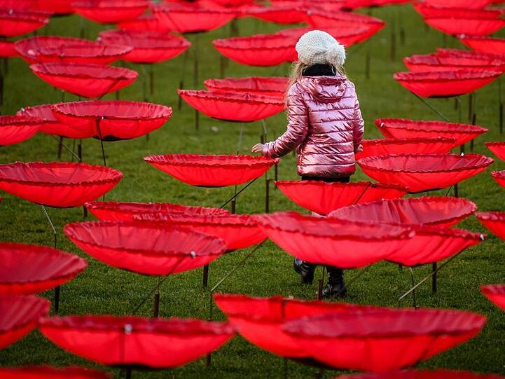 Ein Mädchen läuft zwischen riesigen Mohnblumen der Kunstinstallation "Never again" hindurch. Foto: Matthias Balk/dpa/Archivbild