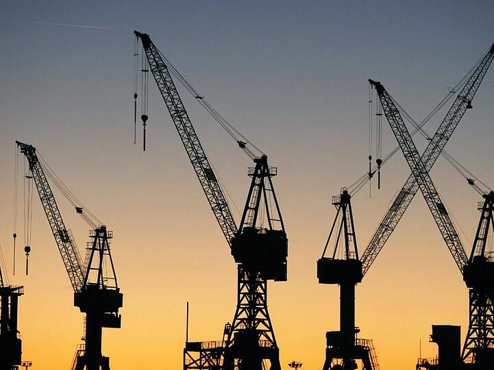 Die Sonne geht hinter Kränen im Hamburger Hafen auf. Die "Wirtschaftsweisen" haben ihre Wachstumsprognose für 2019 deutlich gekappt.