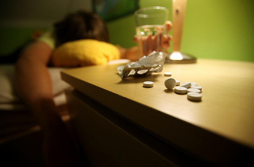 Eine Person liegt nach der Einnahme von Schlaftabletten auf einem Bett (Symbolbild)