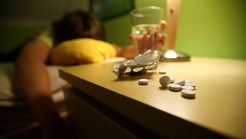Eine Person liegt nach der Einnahme von Schlaftabletten auf einem Bett (Symbolbild) Eine Person liegt nach der Einnahme von Schlaftabletten auf einem Bett (Symbolbild)