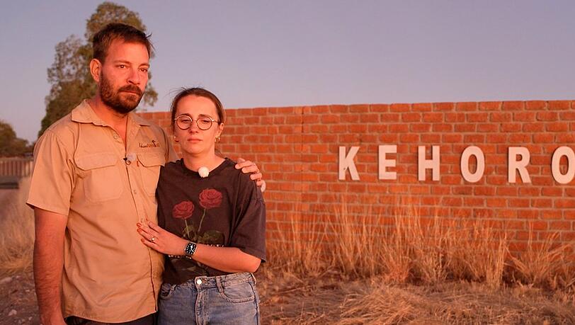 Gerald und Anna stehen ein letztes Mal vor dem Gel&auml;nde ihrer Farm in Namibia.