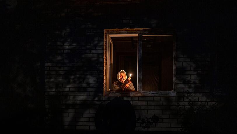 Die 70-Jährige Catherine steht während eines Stromausfalls in Borodjanka mit einer Kerze am Fenster.