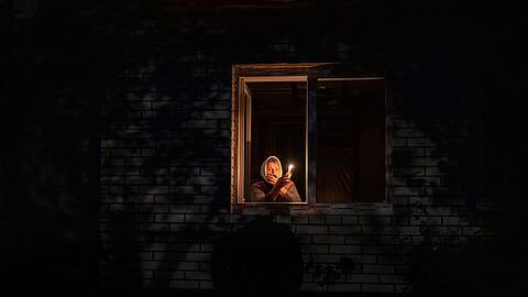 Die 70-Jährige Catherine steht während eines Stromausfalls in Borodjanka mit einer Kerze am Fenster.
