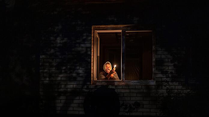 Die 70-Jährige Catherine steht während eines Stromausfalls in Borodjanka mit einer Kerze am Fenster.