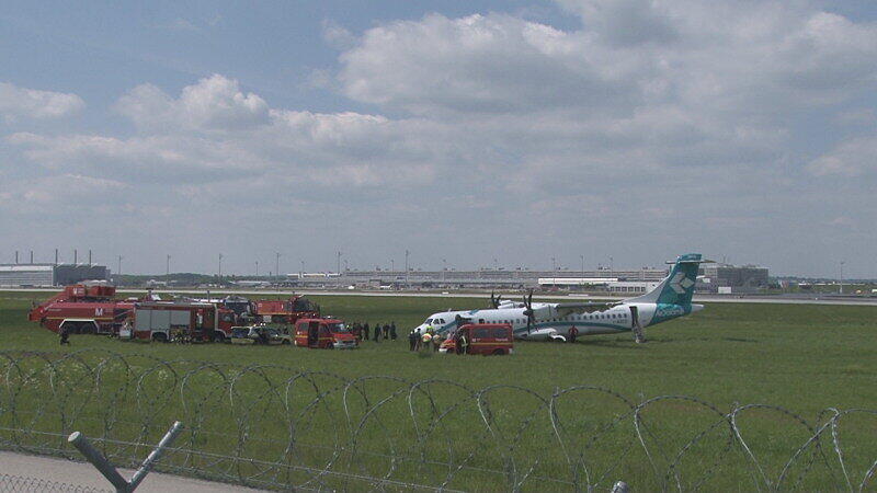 Mitarbeiter des Flughafens in München betrachten die Maschine der italienischen Fluggesellschaft, die am Donnerstag auf dem Münchner Flughafen notlanden musste. Das Flugzeug mit 62 Menschen an Bord hatte kurz nach dem Start in Richtung Venedig umdrehen müssen, weil sich Rauch in der Kabine entwickelt hatte. Bei der Landung wurden fünf Personen leicht verletzt, die Maschine kam neben der Landebahn zum Stehen.