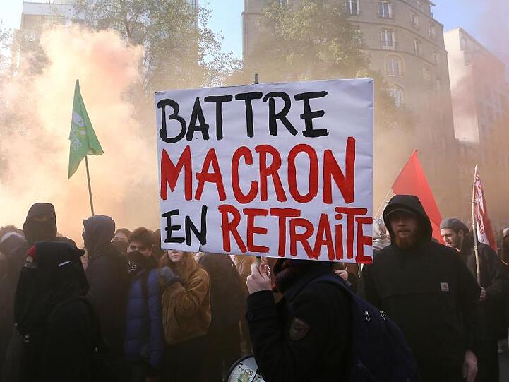 Demonstranten tragen ein Plakat mit der Aufschrift "Battre Macron en Retraite" (sinngemäß: "Macron zum Rücktritt zwingen").