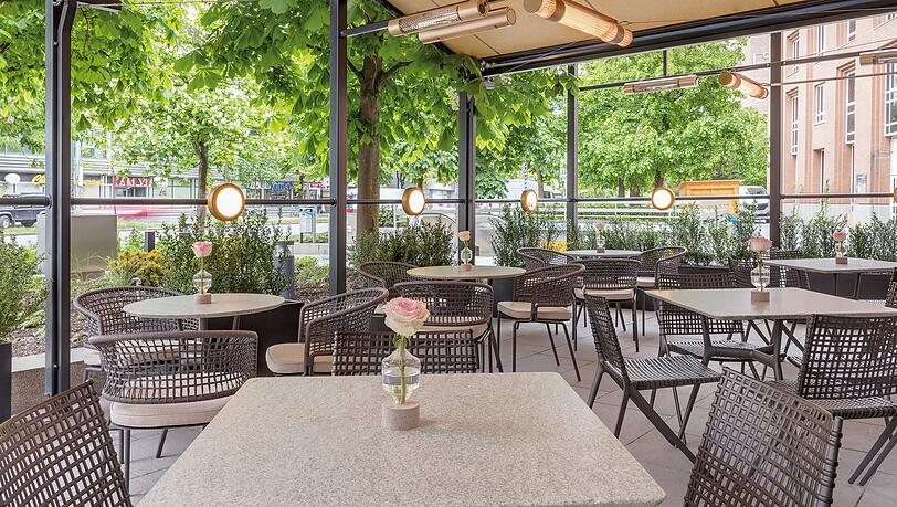 Bei sch&ouml;nem Wetter k&ouml;nnen die G&auml;ste auch drau&szlig;en sitzen. Die trubelige Rosenheimer Stra&szlig;e wird mit vielen Pflanzen abgeschirmt.