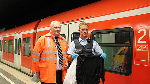 Erich Brzosa, der Leiter der DB Netz AG für den Großraum München (l.) mit einem Polizeibeamten, der die Jacke in der Hand hält, die für die Stammstreckensperrung verantwortlich ist.