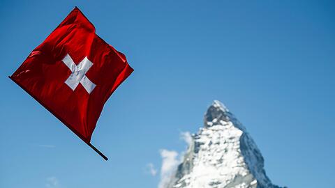 Ein Fahnenwerfer mit der Schweizer Flagge in Aktion vor der Kulisse des Matterhorns.
