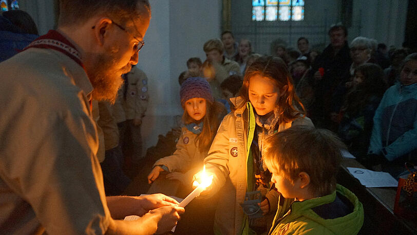 Pfadfinder in der Frauenkirche mit dem Friedenslicht von Bethlehem, das an Gläubige weitergegeben wird.
