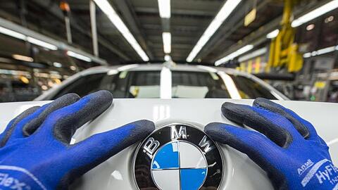 Ein Mitarbeiter montiert ein BMW-Emblem auf den Kofferraumdeckel eines Fahrzeugs der 7er Reihe. Foto: Armin Weigel/Archiv