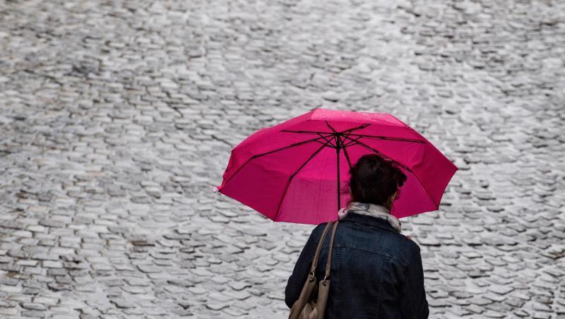 Ein Frau geht mit Regenschirm über eine Straße. Foto: Hendrik Schmidt/Archiv Ein Frau geht mit Regenschirm über eine Straße. Foto: Hendrik Schmidt/Archiv