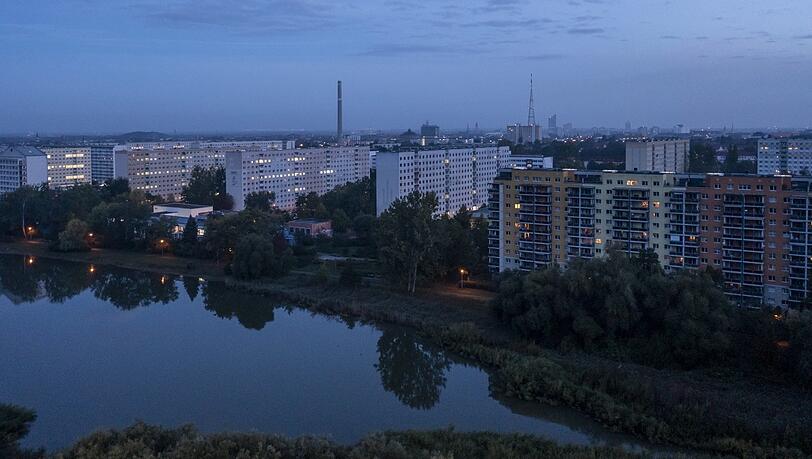 Ein Wohngebiet in Leipzig am Morgen - erste Wohnungen werden beleuchtet. Die Kosten für Gas und Strom belasten die Bürger finanziell enorm - eine Gasumlage sehen viele kritisch.