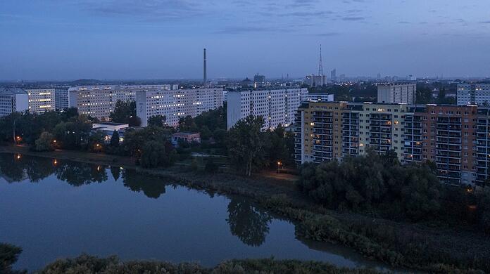 Ein Wohngebiet in Leipzig am Morgen - erste Wohnungen werden beleuchtet. Die Kosten für Gas und Strom belasten die Bürger finanziell enorm - eine Gasumlage sehen viele kritisch.