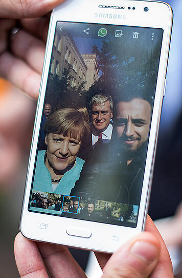 Rodin Saouan, Flüchtling aus Syrien, zeigt am 10.09.2015 in Berlin auf seinem Smartphone ein Selfie-Foto, welches er kurz zuvor zusammen mit Bundeskanzlerin Angela Merkel (CDU) gemacht hat.