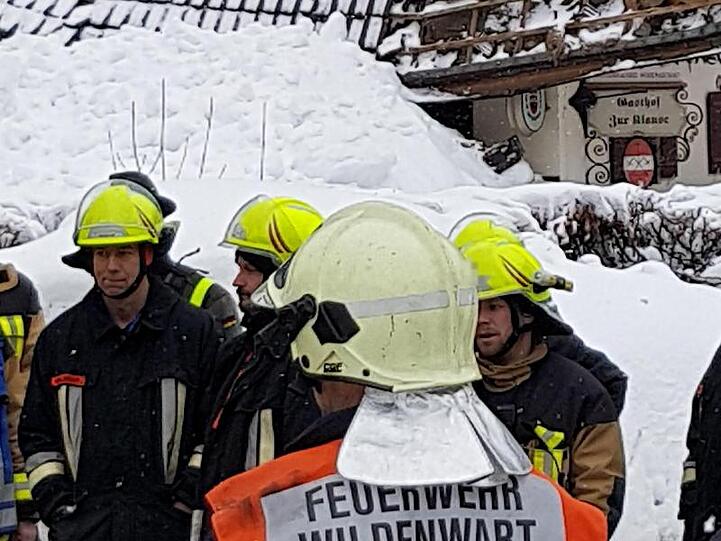 Feuerwehrleute stehen an einer Einsatzstelle im Chiemgau, an der das Dach eines Hauses teilweise eingestürzt ist. Foto: Josef Reisner