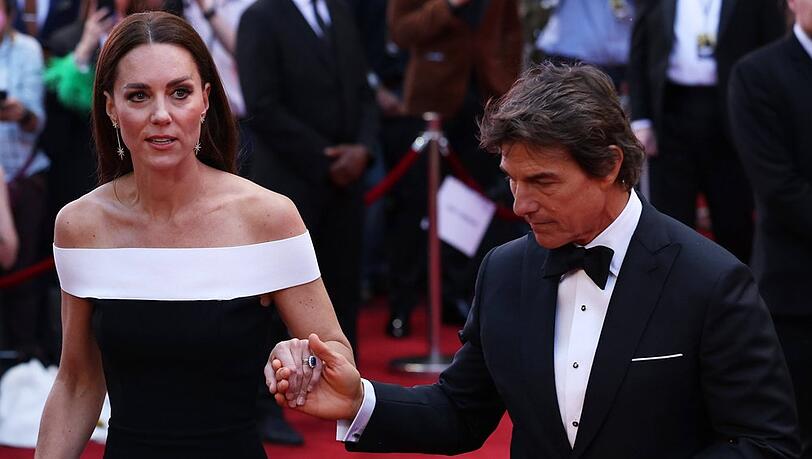Tom Cruise hilft Herzogin Kate auf dem roten Teppich die Treppen hoch.
