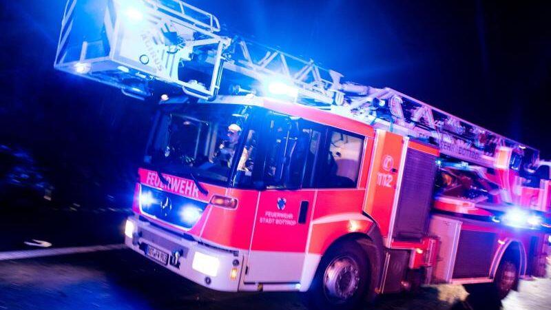 Ein Drehleiterwagen der Feuerwehr fährt mit Blaulicht an einer Unfallstelle vorbei. Foto: Marcel Kusch/dpa