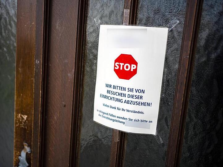 An einer Zugangstür zu einem Würzburger Seniorenheim ist ein Schild angebracht, das von Besuchen abrät. Foto: Nicolas Armer/dpa/Archivbild