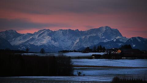 Vom Sonnenaufgang rot gefärbte Wolken sind vom Landkreis Bad Tölz-Wolfratshausen aus über den Alpen zu sehen.